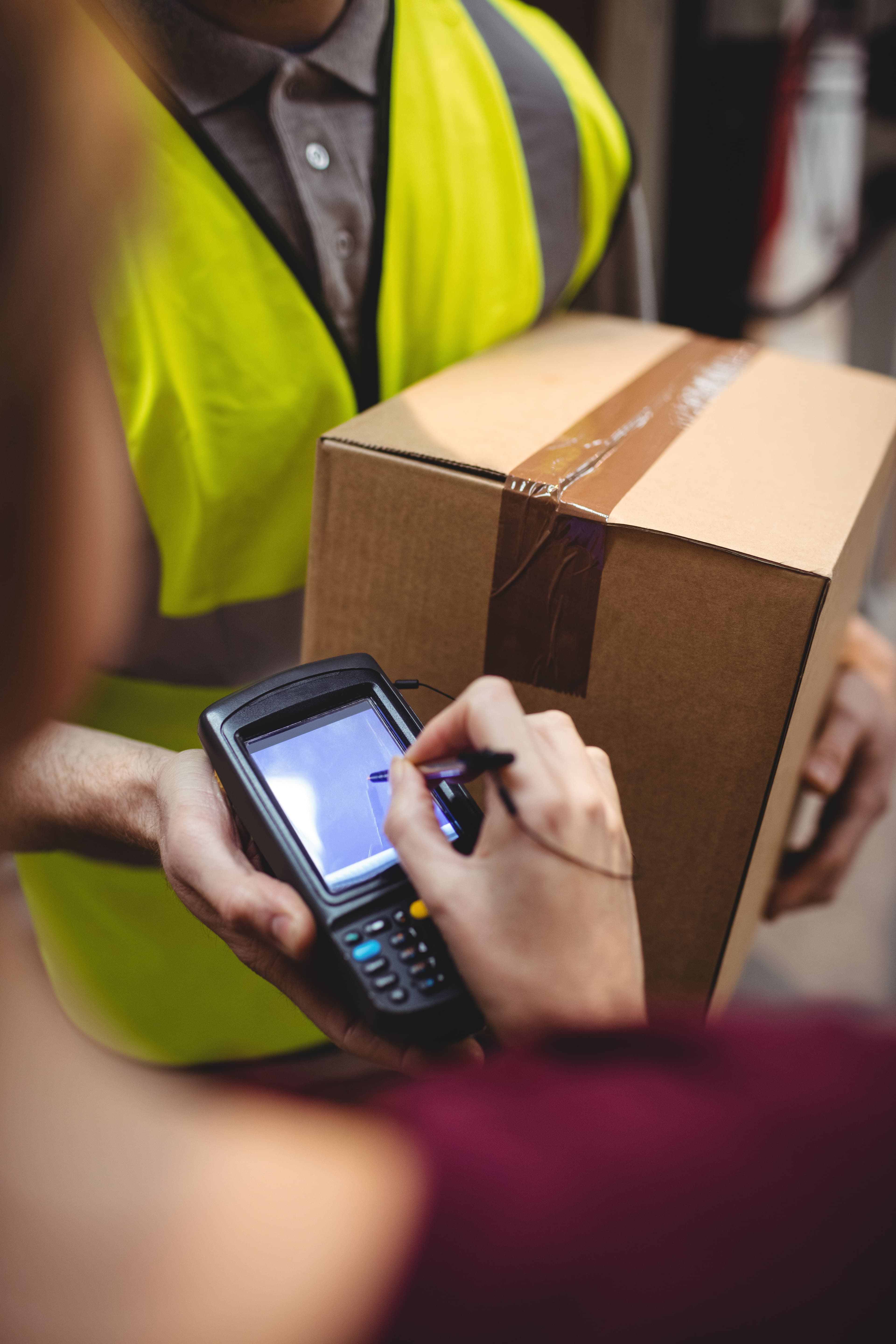 Courier driver getting a signature from a customer before handing over a parcel