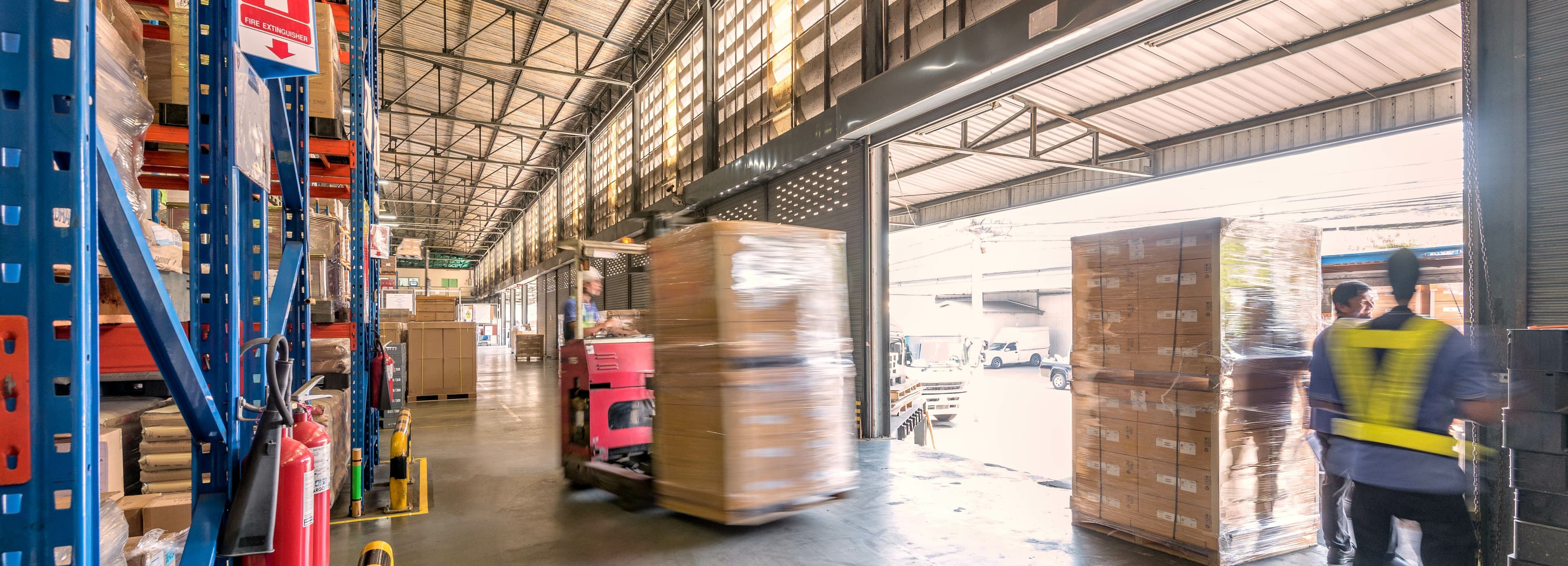 A busy warehouse with someone moving pallets ready for dispatch 