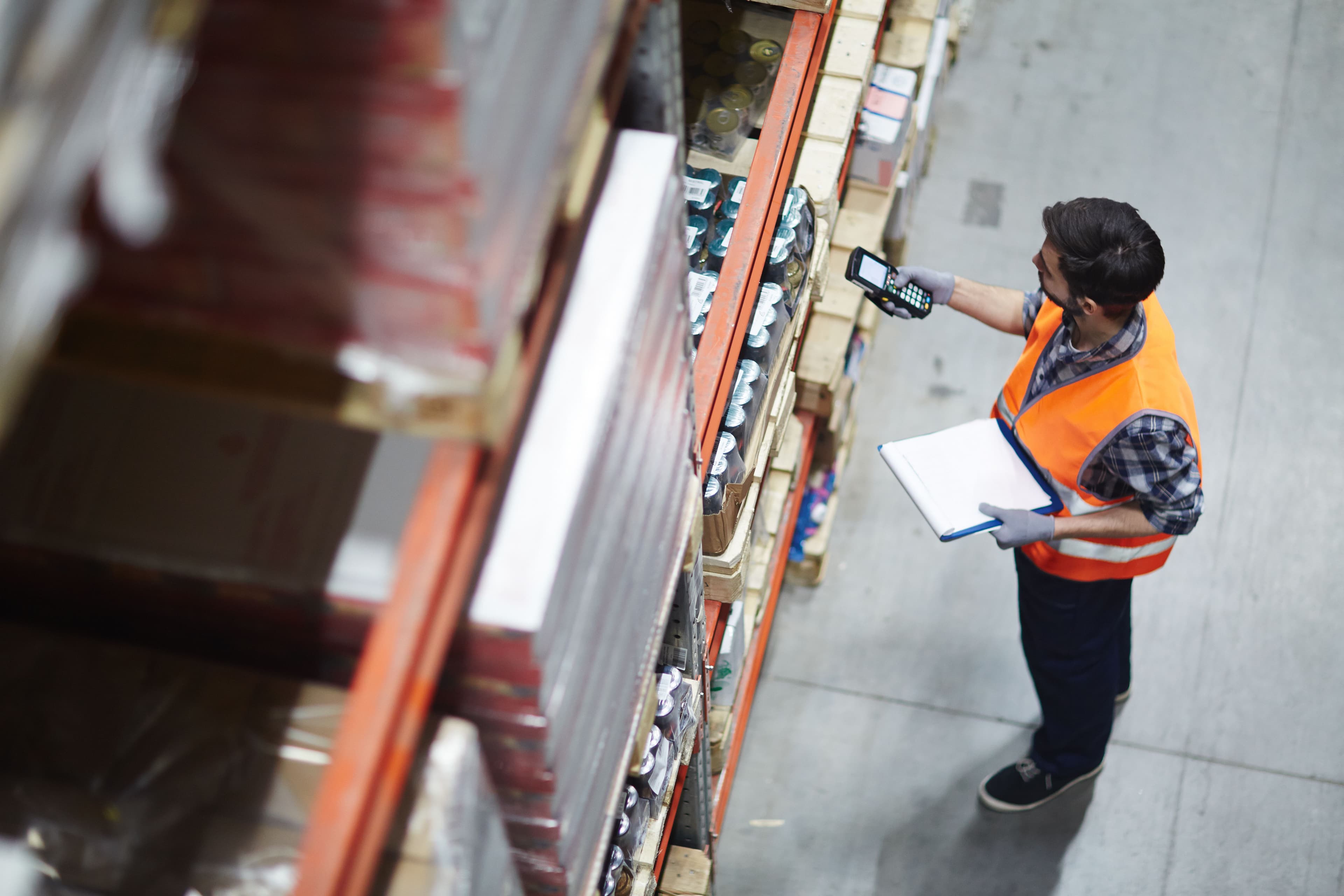 A warehouse working wearing a hi vis scanning items on shelves