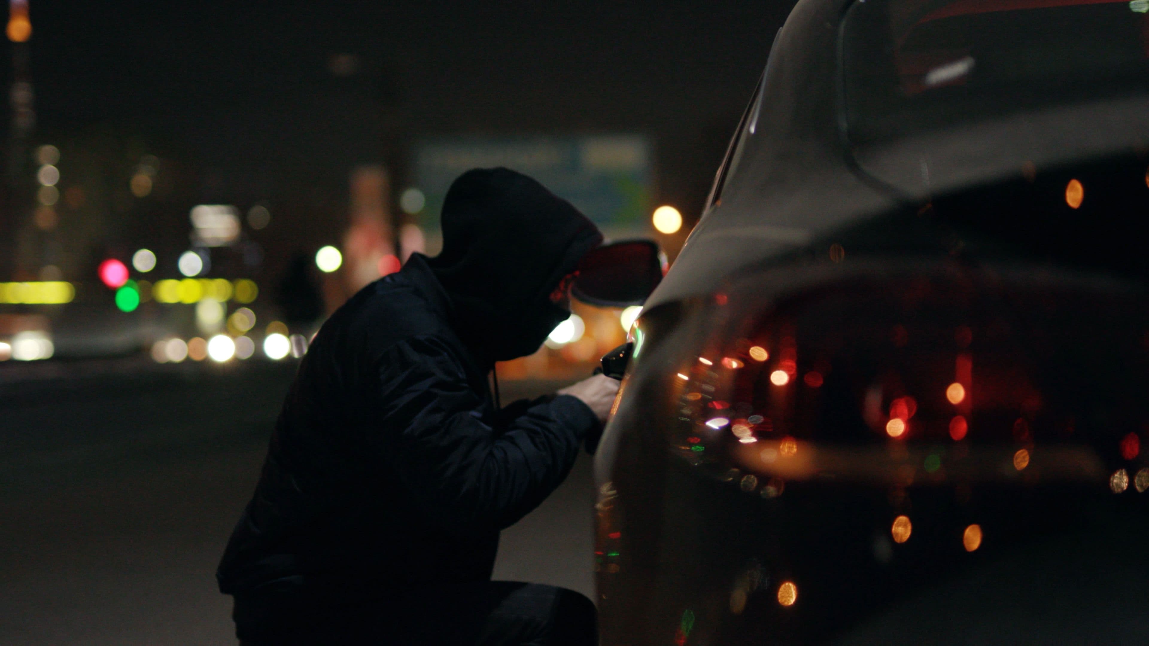 A person trying to force entry into a vehicle at night