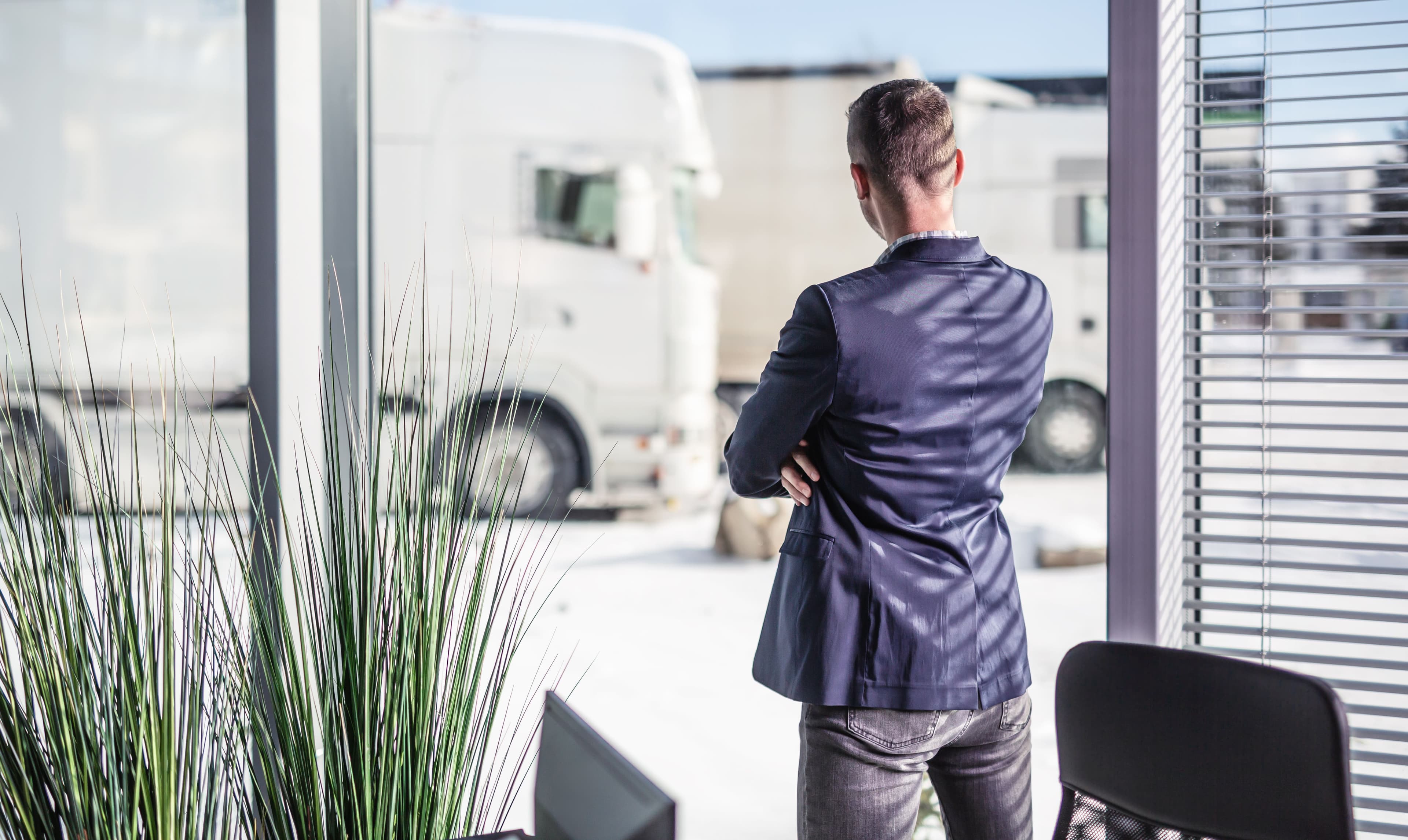 A business person looking outside at two HGVs