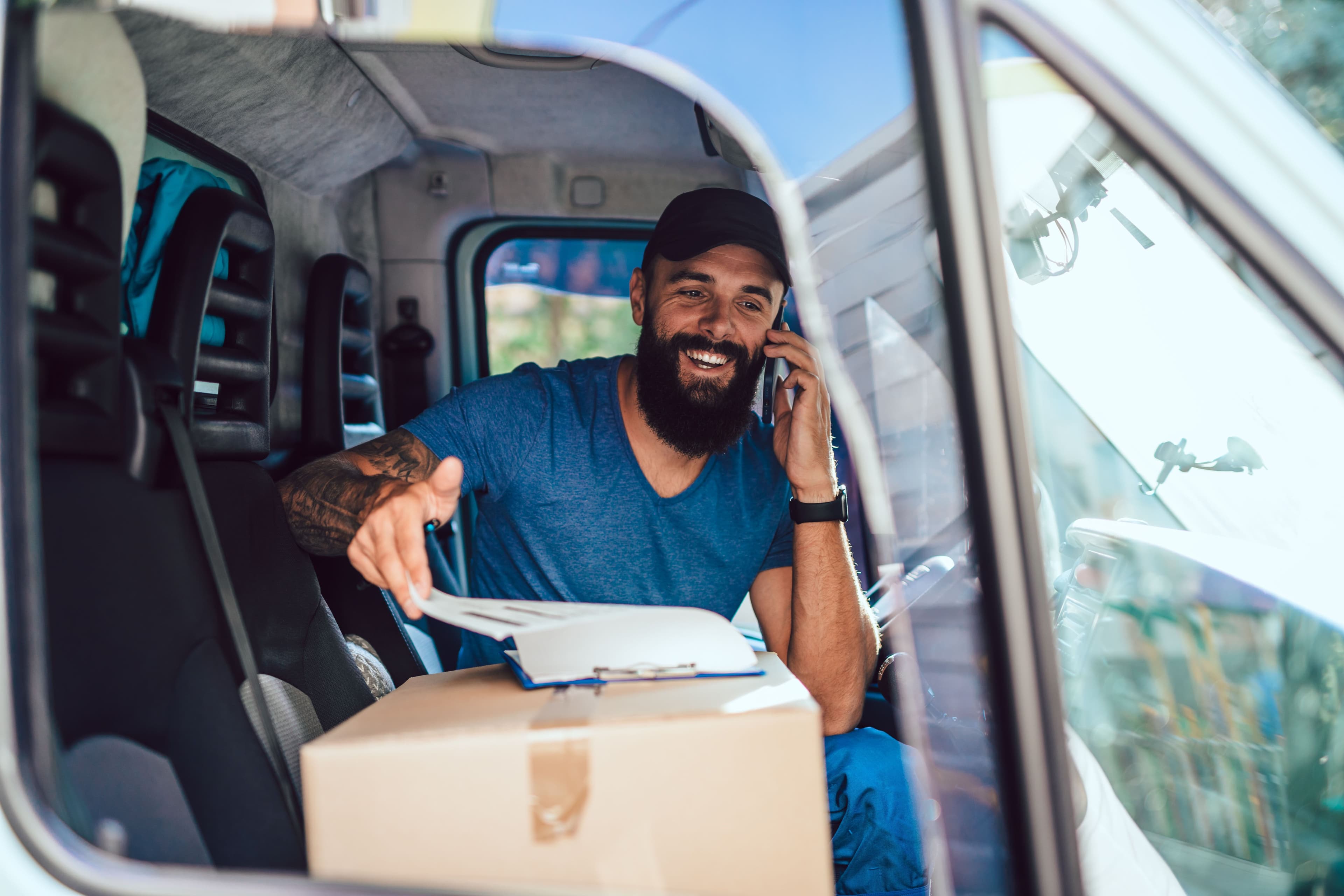 Courier driver in the front seat of their van while on the phone talking