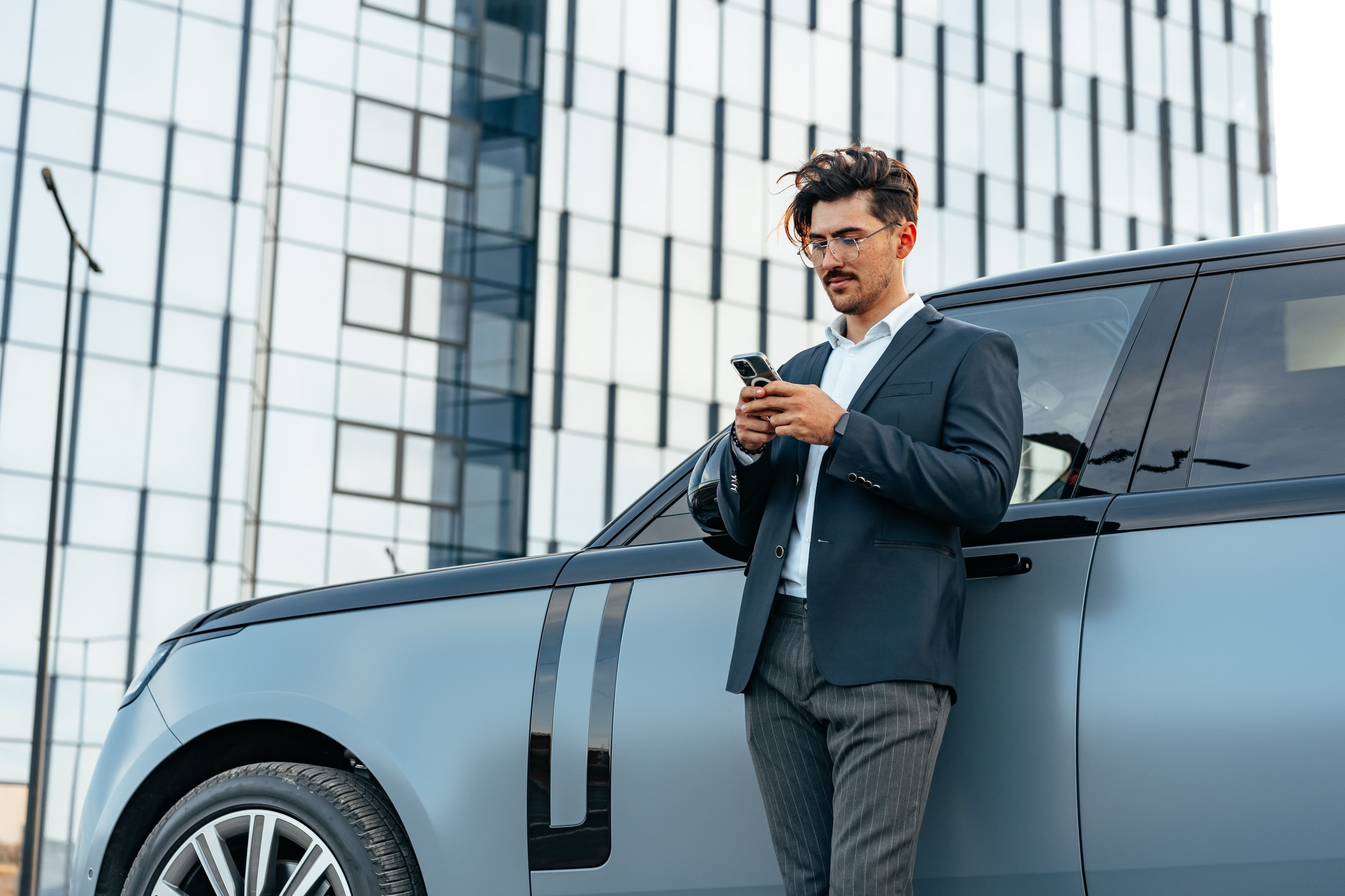 A person stood next to a vehicle on the phone 