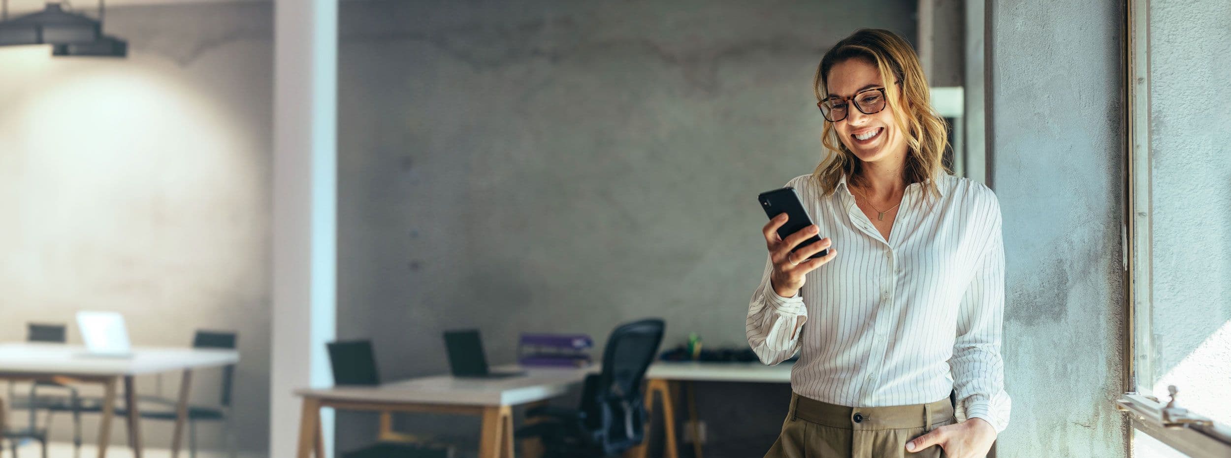 Someone standing in an empty office using a phone