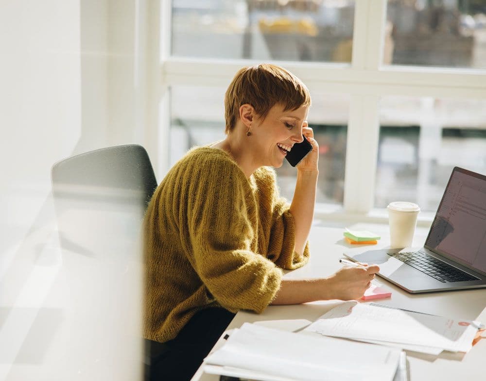 One person sat at their desk on the phone making notes