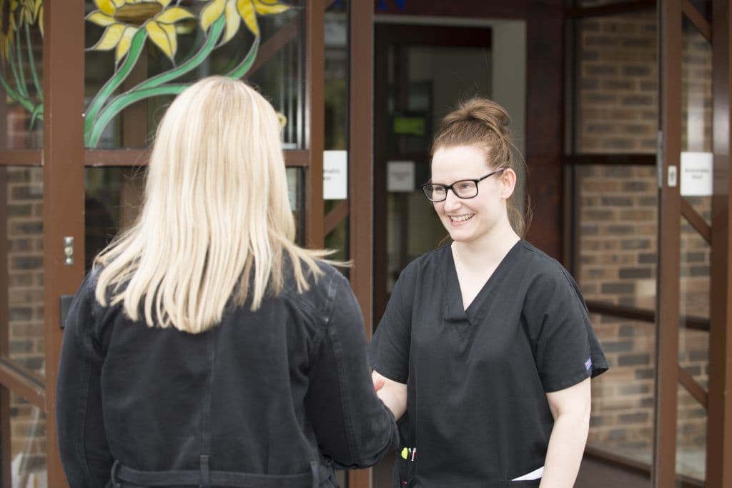East Cheshire Hospice worker supports a visitor, shaking hands with them