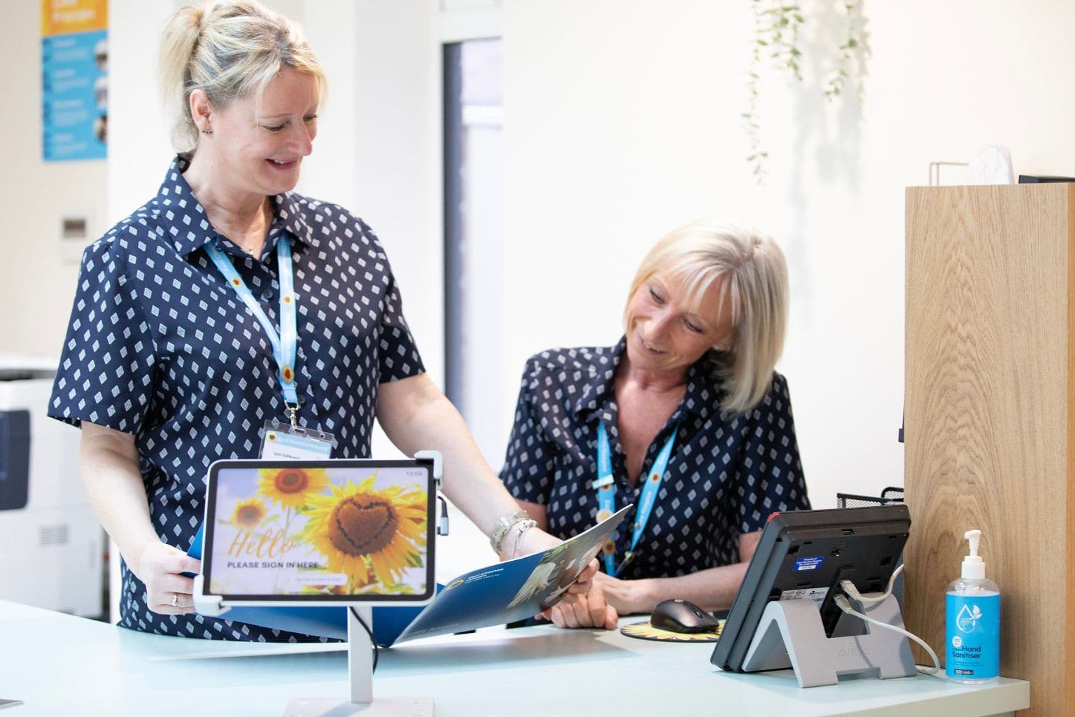 Two women sat reviewing a brochure at the reception desk of East Cheshire Hospice