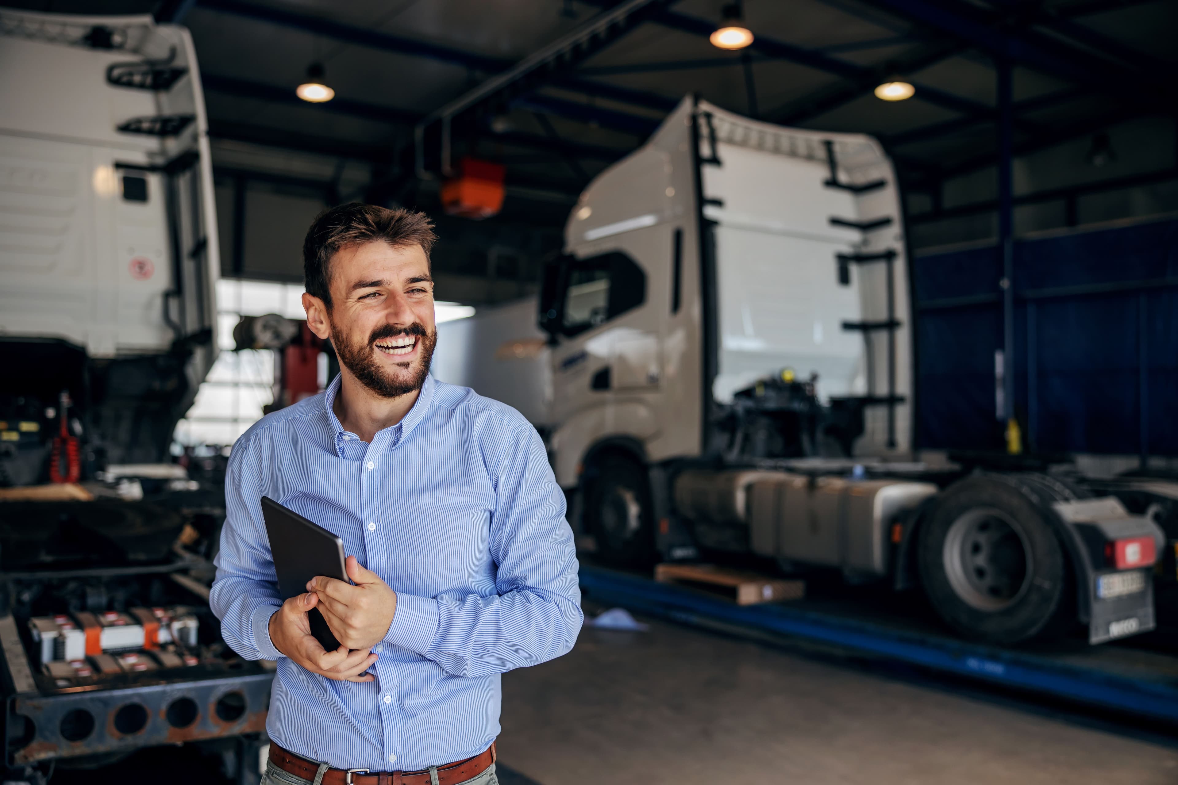 A businessperson in a HGV garage holding a tablet