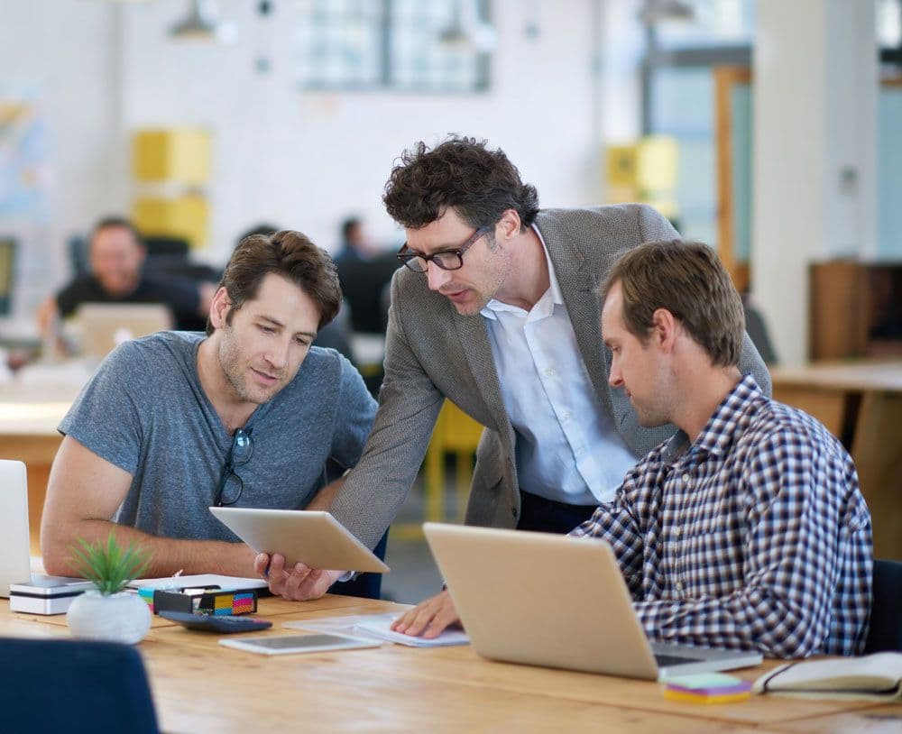 Three people in an office looking over a tablet