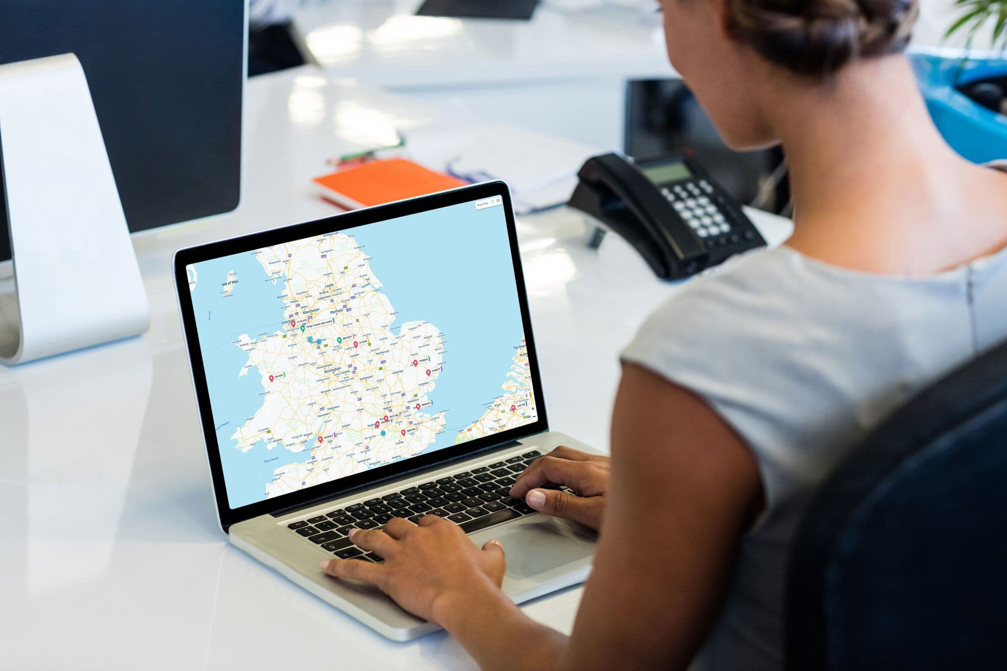 A businessperson sitting at a desk using a laptop to load a map