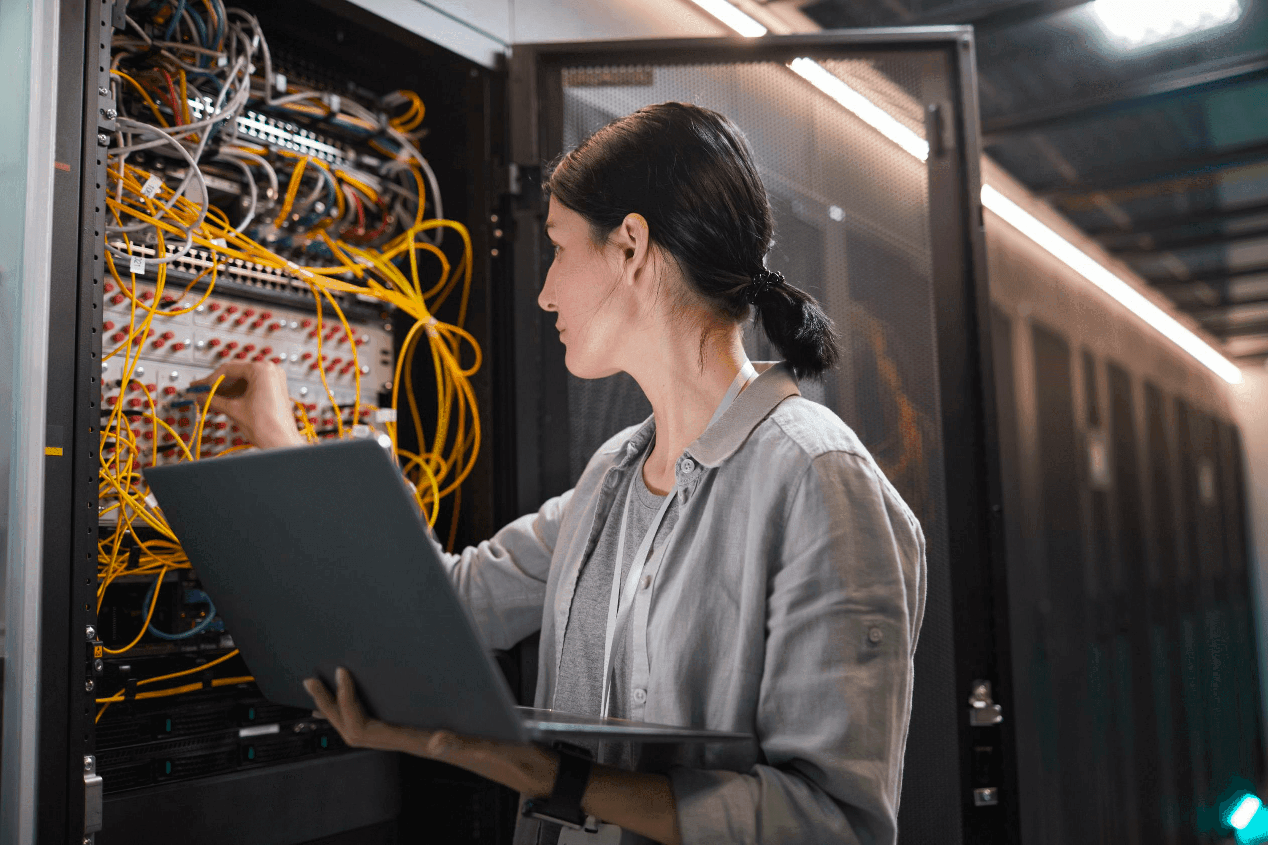 One person working on a computer server holding a laptop