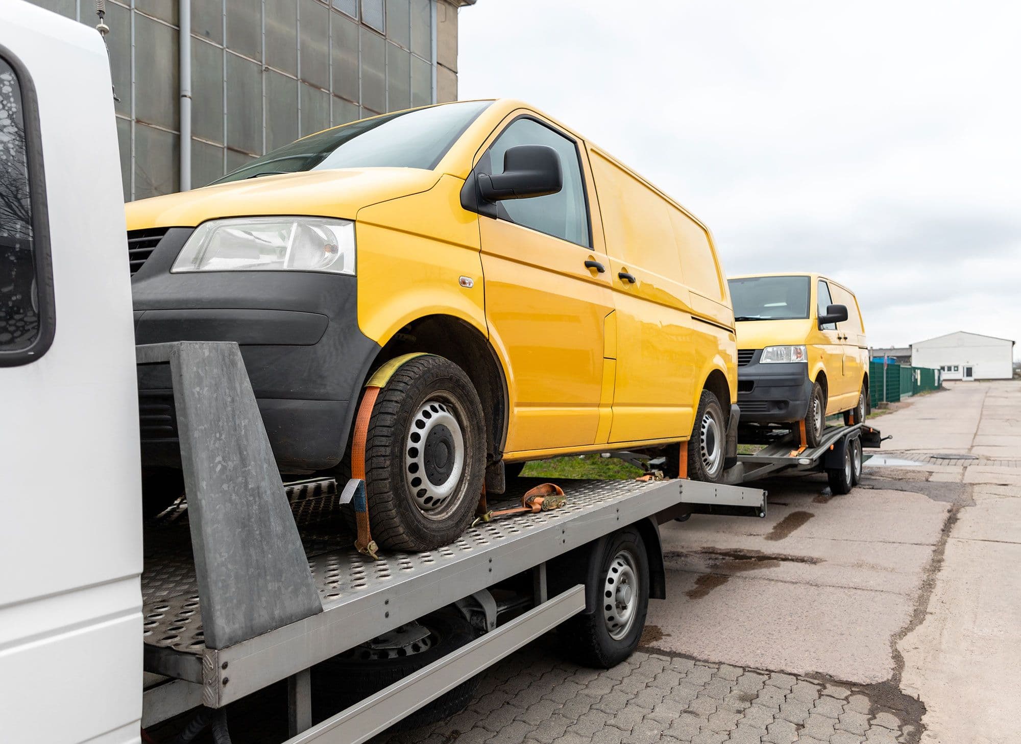 Two vans on the back of a flatbed truck