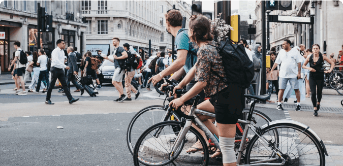 Two people on a bike waiting for pedestrians to cross the road