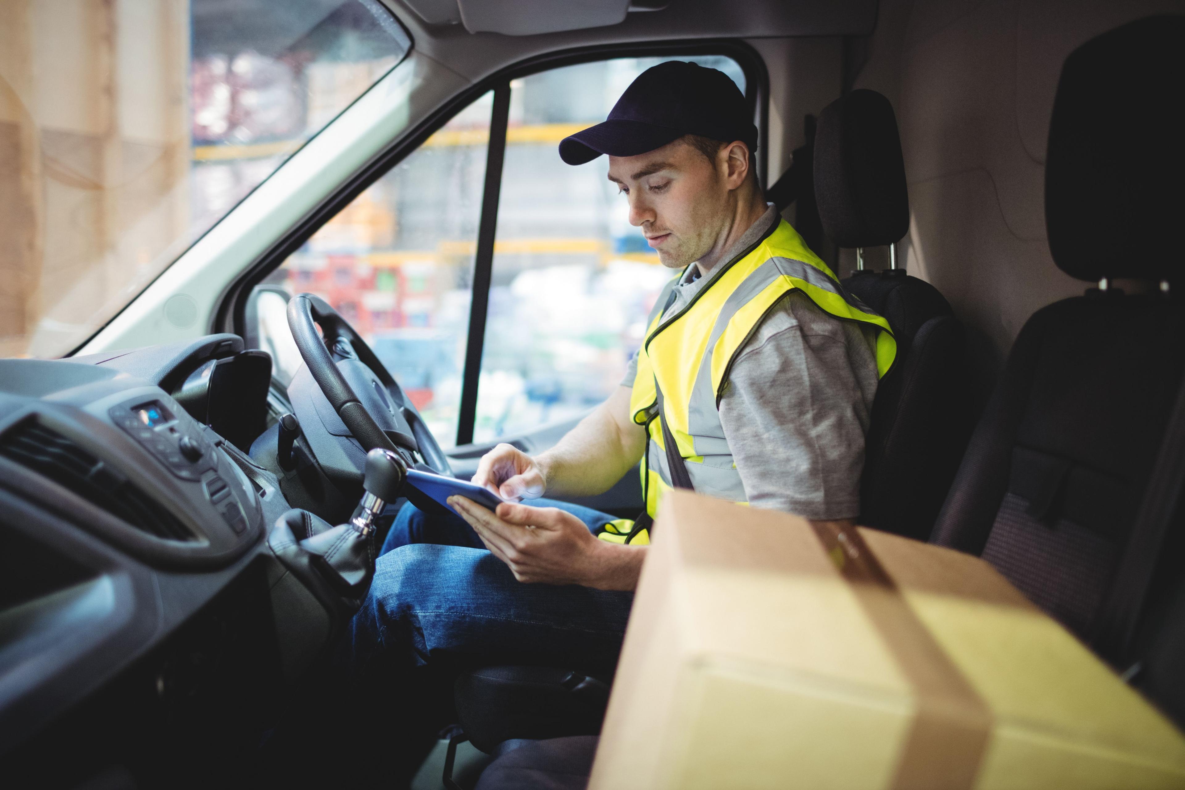Courier driver in the front seat of their van using a mobile device
