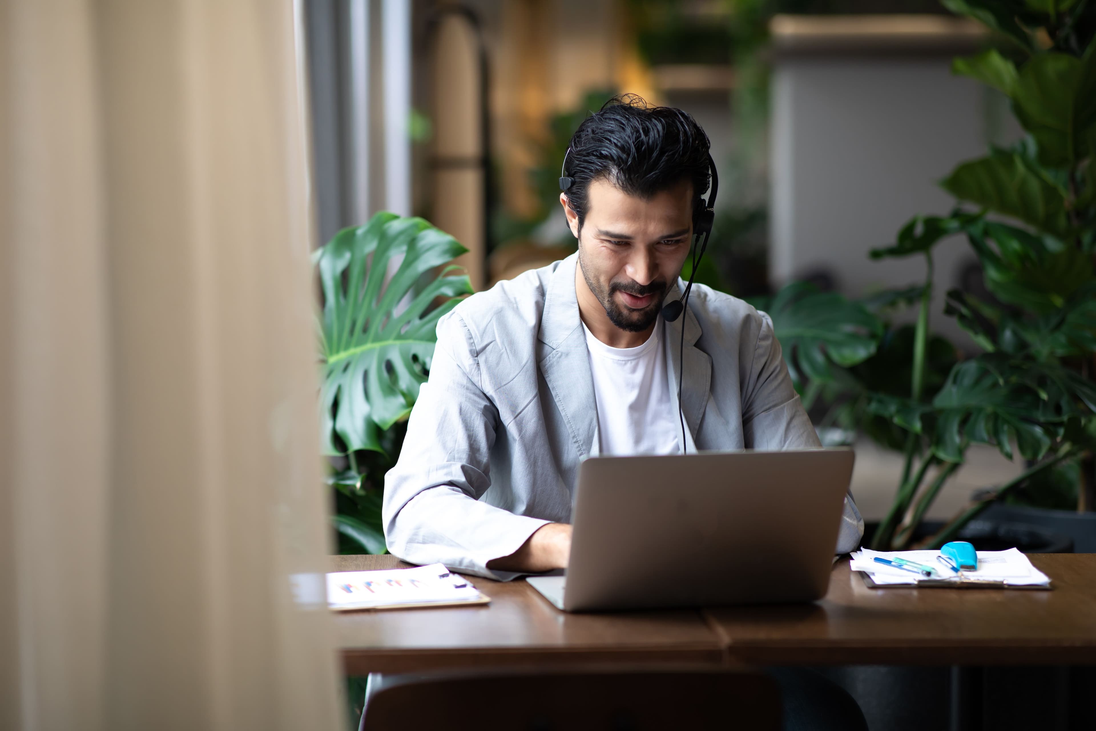 A person sat at a desk with a laptop with their headset on