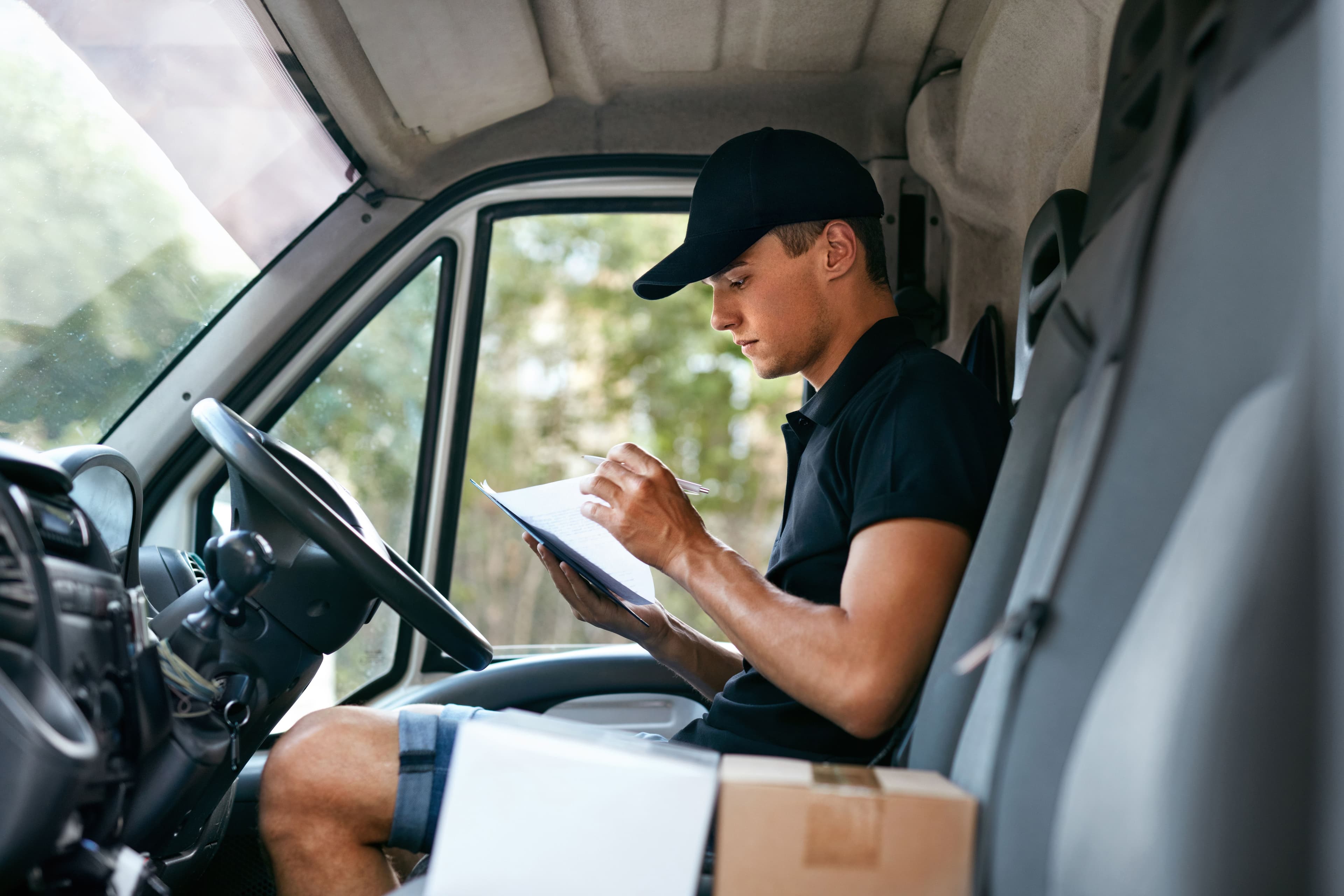 Courier driver in the front seat of their van looking over paperwork