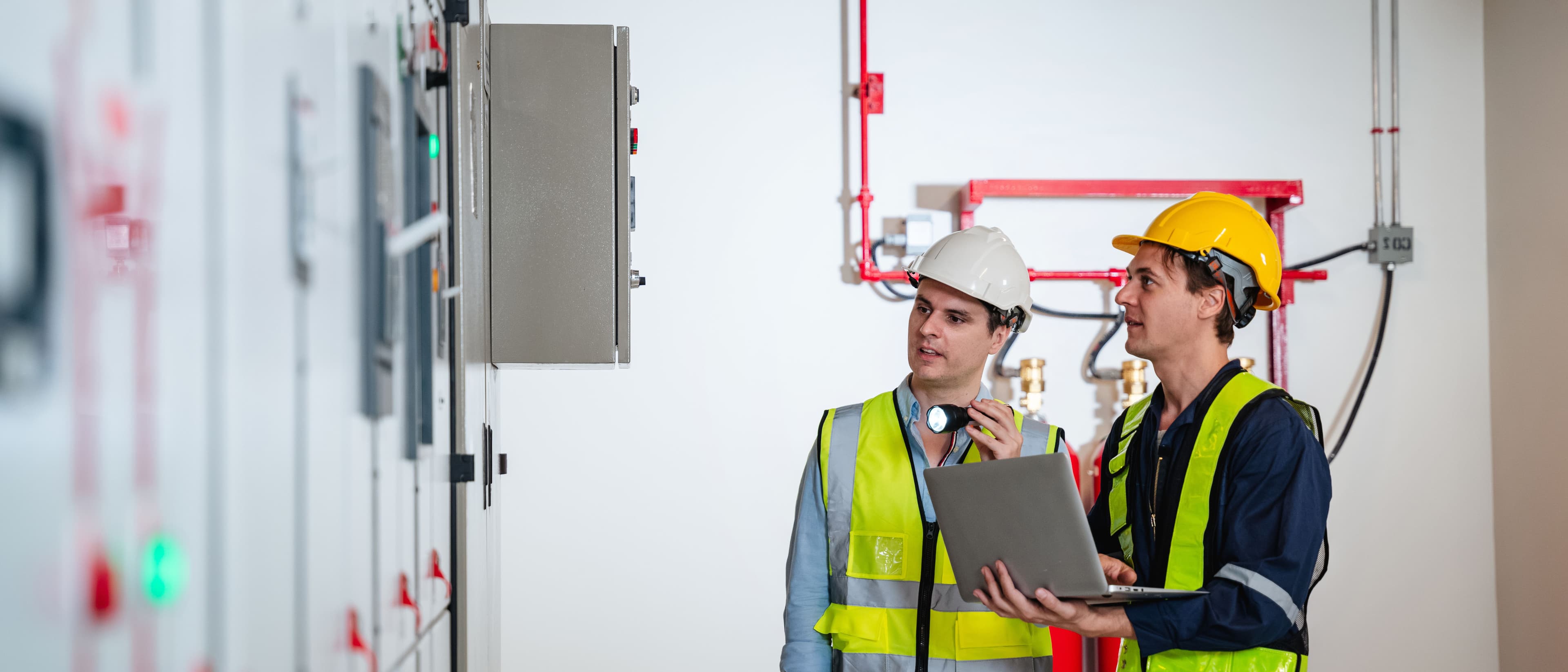 Two people inspecting a control panel