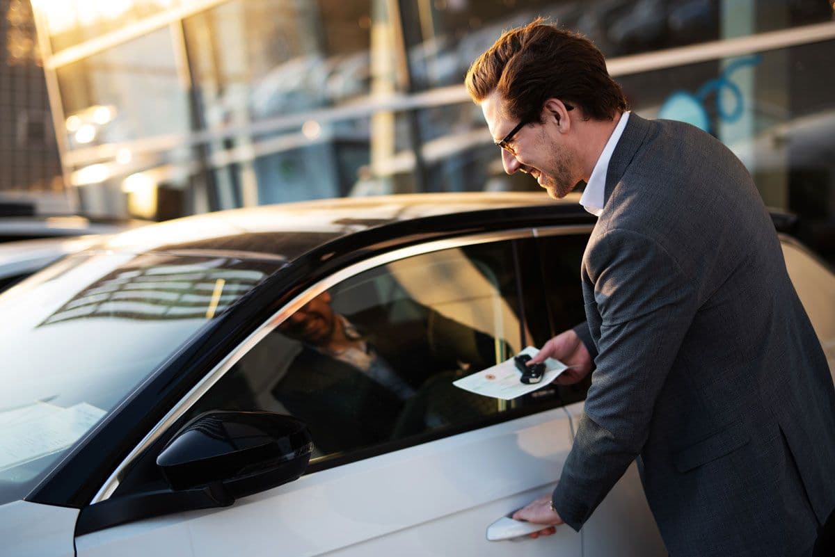 A person wearing a suit about to get into a car