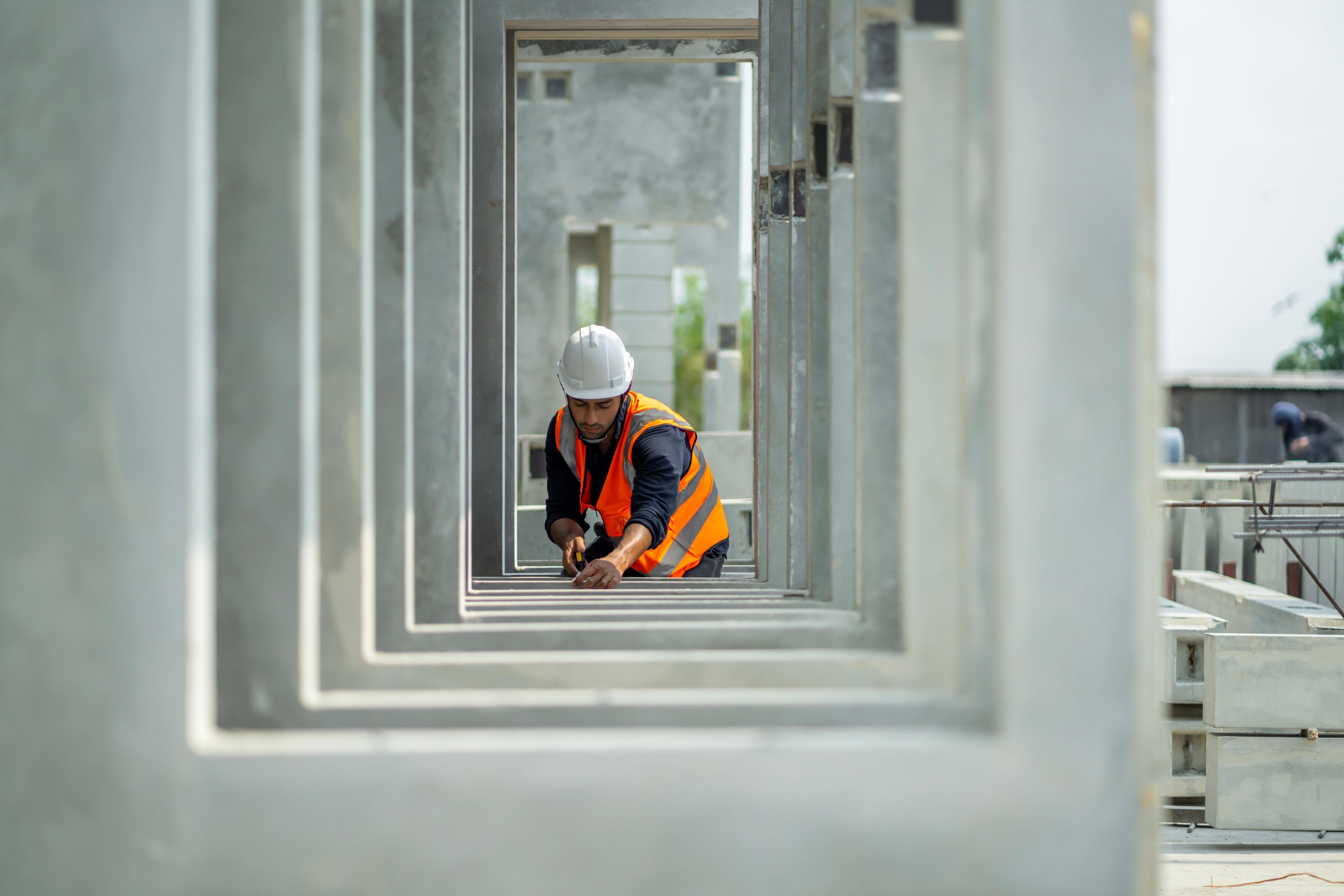 A person wearing a hard-hat and hi vis inspecting building work