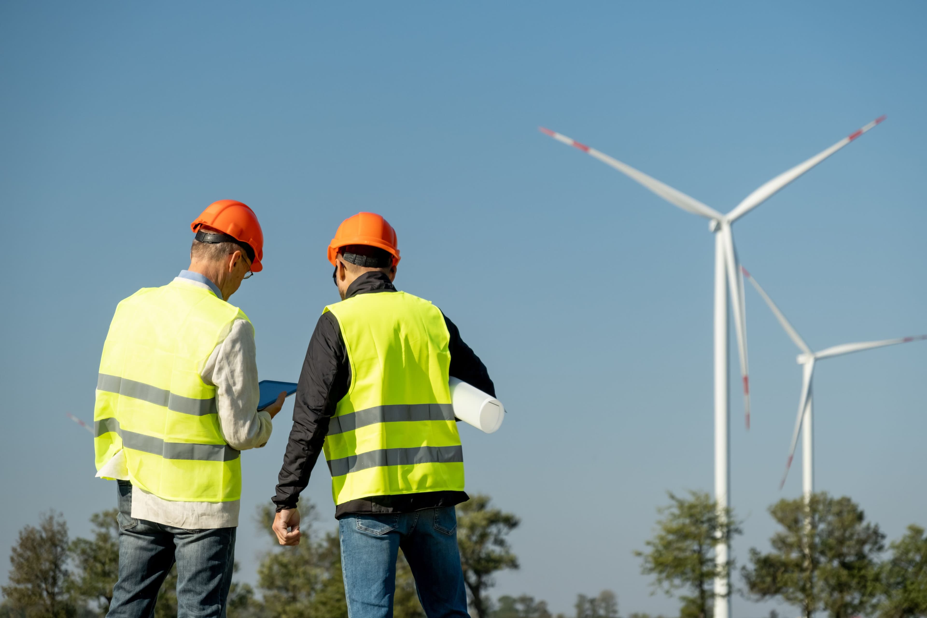 Two people looking at a wind turbine in the distance