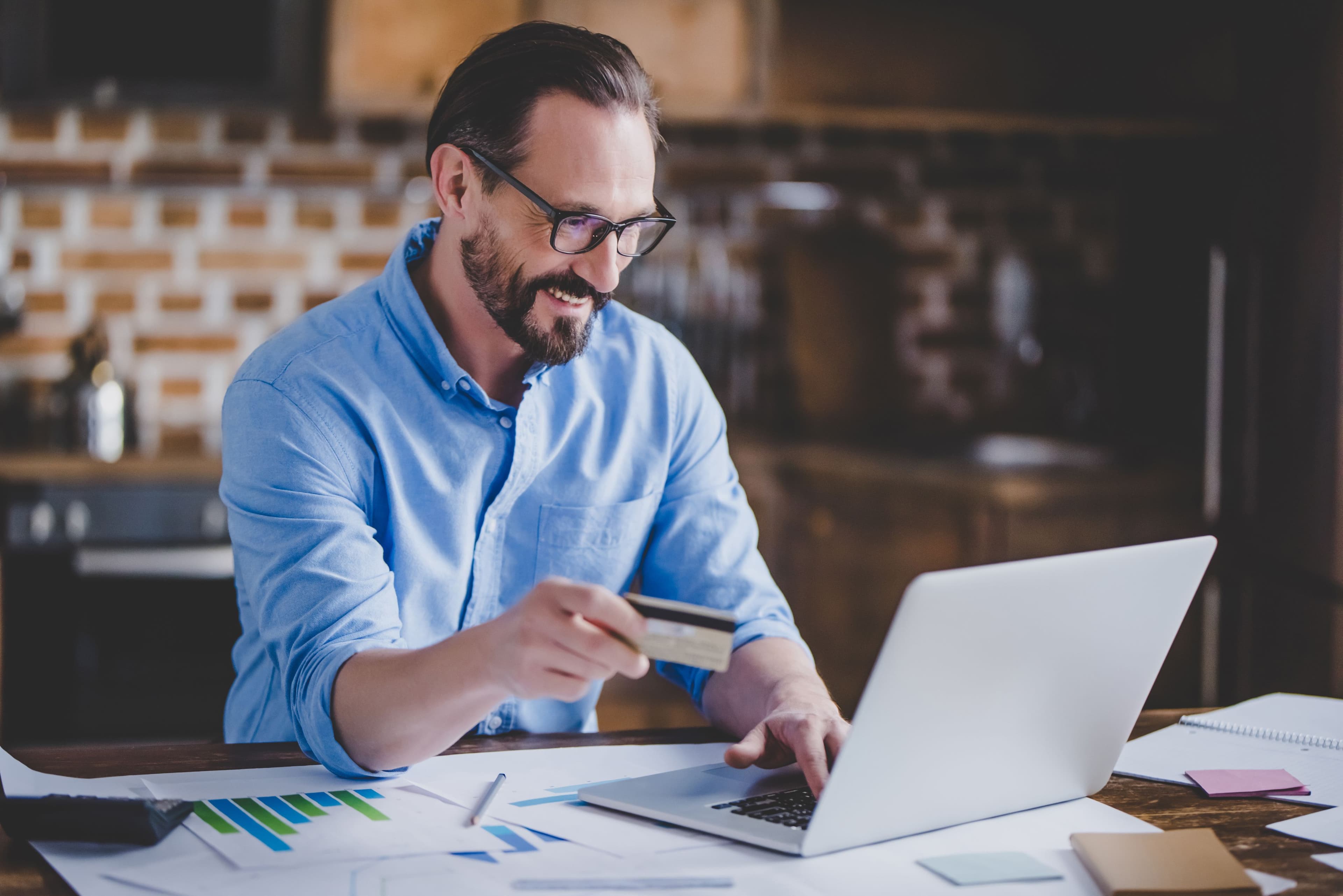 A businessperson working in a kitchen with their laptop and paper over the tops