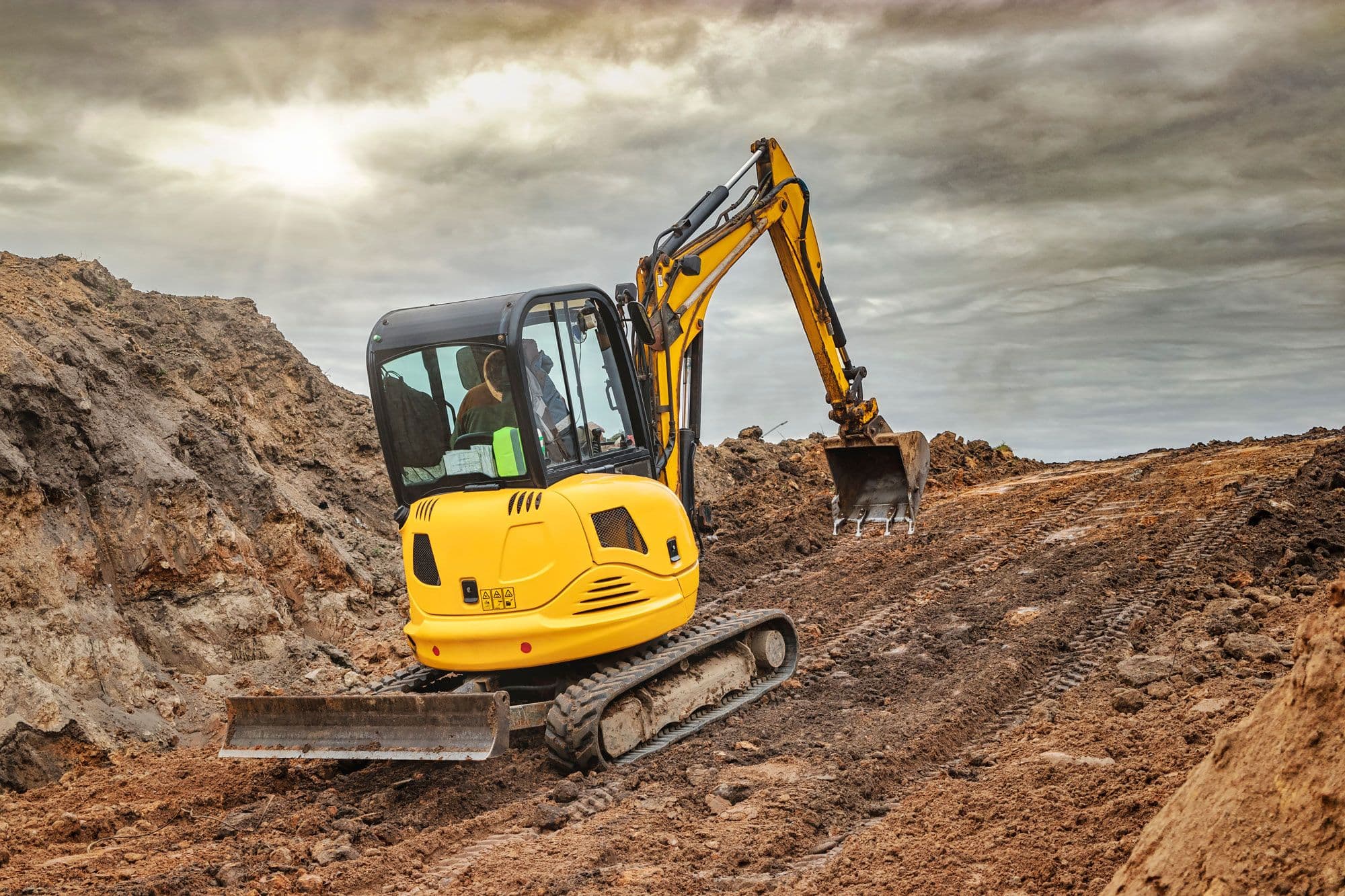 Mini excavator climbing up a mud hill