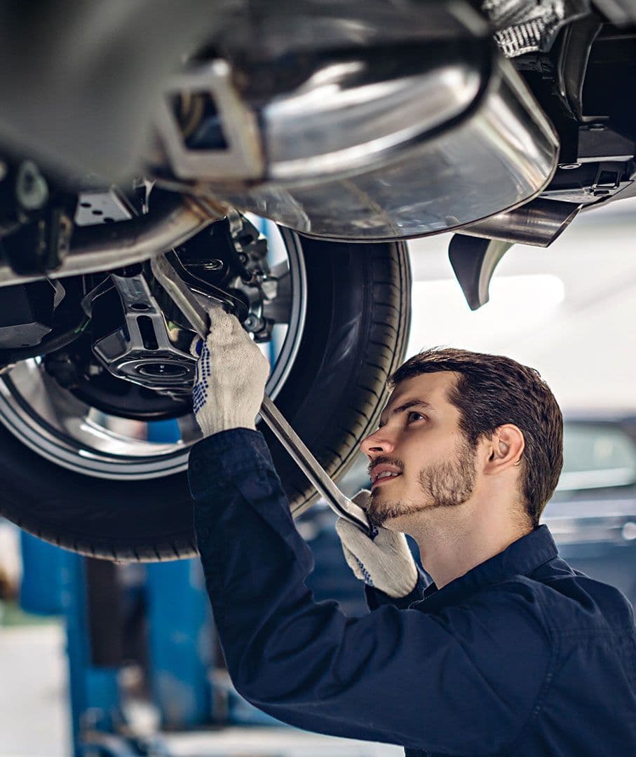 A mechanic inspecting underneath a vehicle