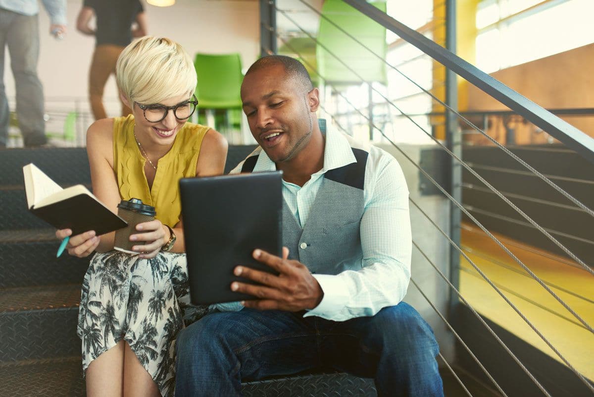 Two people sitting on steps discussing business 