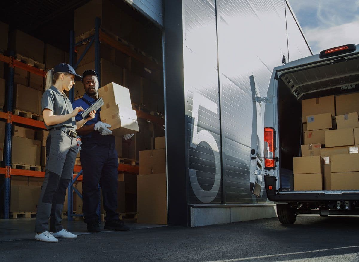 Two people standing outside a small warehouse